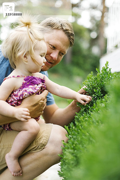 Vater spielt mit einem kleinen Mädchen (12-17 Monate) im Hinterhof