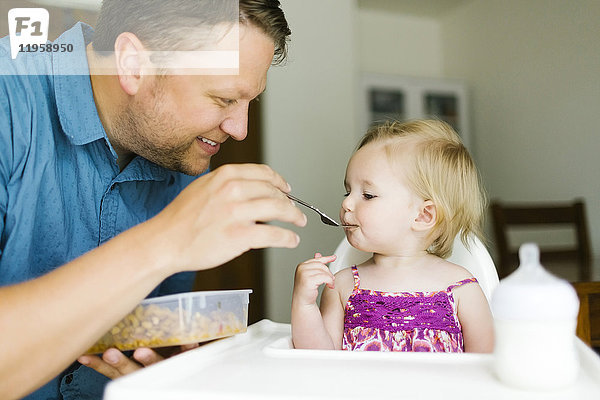 Vater füttert kleines Mädchen (12-17 Monate)