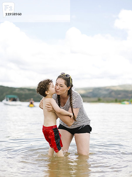 Mutter küsst Sohn (4-5) beim Waten im See