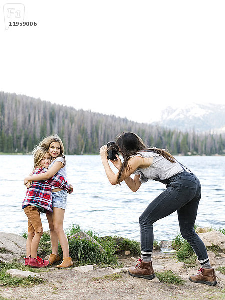 Mutter fotografiert Mädchen (8-9) und Jungen (6-7) am See