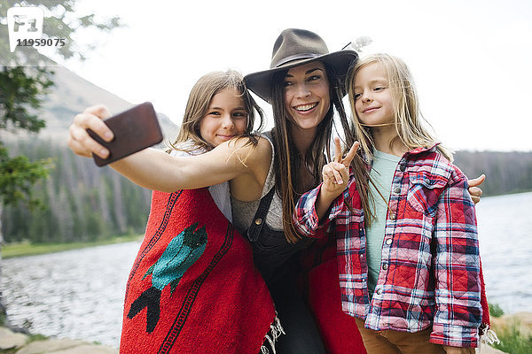 Outdoor-Porträt von Mutter mit Kindern (6-7  8-9)  die ein Selfie am See machen