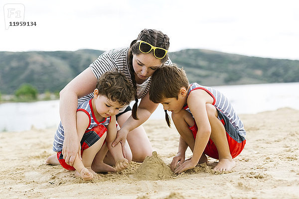 Mutter spielt mit Söhnen (4-5  6-7) am Strand am See