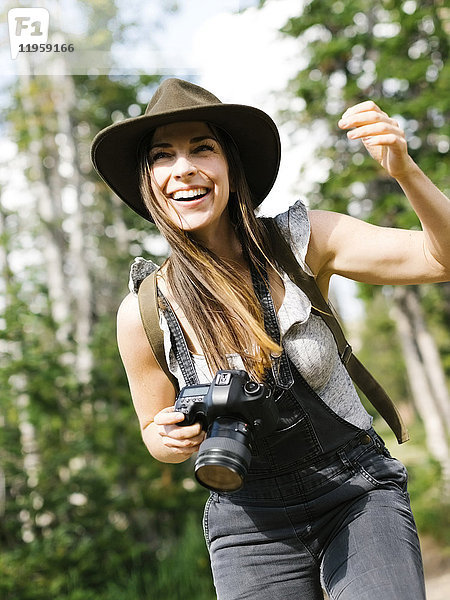 Frau mit Kamera beim Wandern im Wald