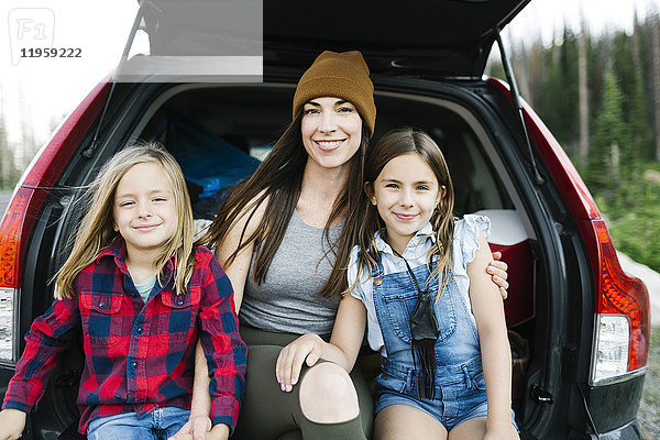 Porträt einer Frau mit Sohn (6-7) und Tochter (8-9) auf der Rückbank eines Autos