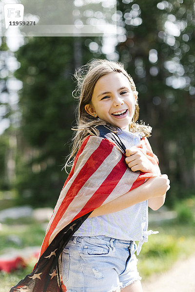 Porträt eines Mädchens (8-9)  eingewickelt in unsere Flagge im Wald