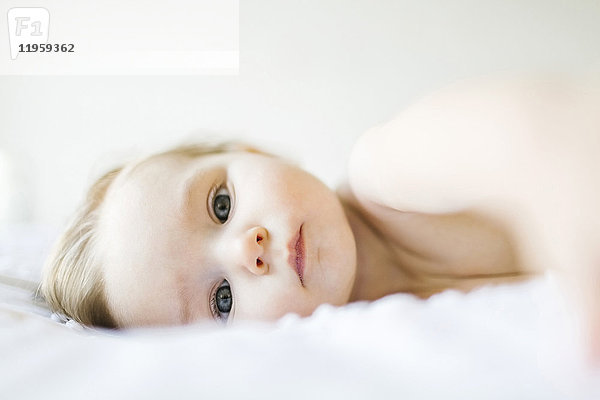 Porträt eines kleinen Mädchens (6-11 Monate) auf dem Bett liegend