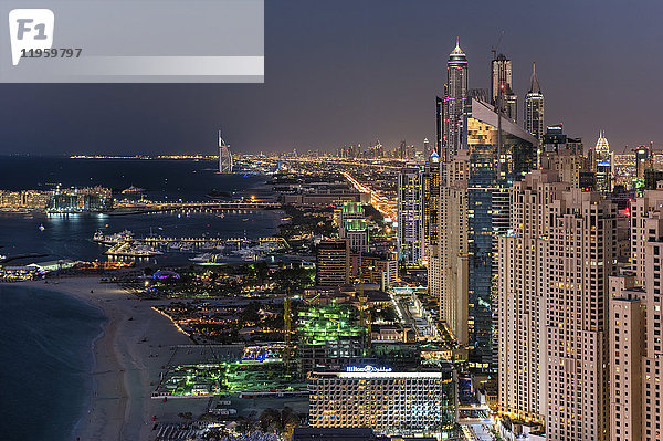 Stadtbild von Dubai  Vereinigte Arabische Emirate in der Abenddämmerung  mit beleuchteten Wolkenkratzern und der Küstenlinie des Persischen Golfs.