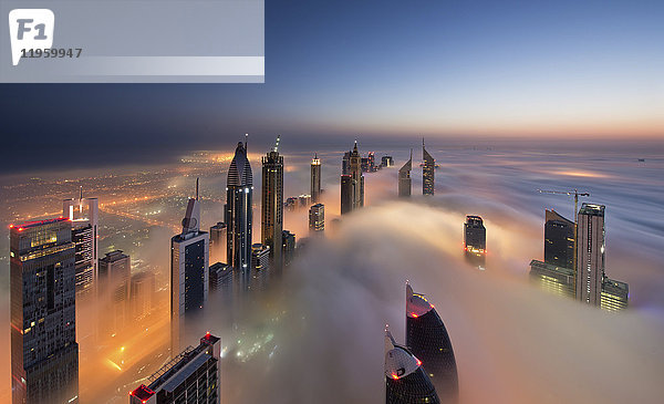 Blick auf beleuchtete Wolkenkratzer über den Wolken in Dubai  Vereinigte Arabische Emirate in der Abenddämmerung.