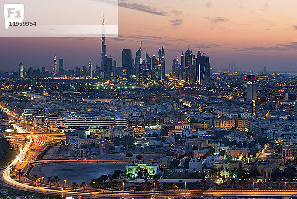 Stadtbild von Dubai  Vereinigte Arabische Emirate in der Abenddämmerung  mit der Autobahn im Vordergrund und Wolkenkratzern in der Ferne.