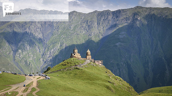 Dreifaltigkeitskirche von Gergeti auf dem Berg Kazbegi in der Nähe des Dorfes Gergeti  Georgien  mit Bergen in der Ferne.