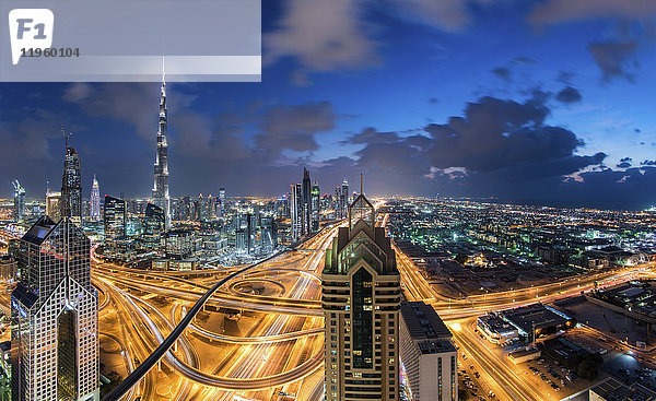 Stadtbild von Dubai  Vereinigte Arabische Emirate in der Abenddämmerung  mit dem Burj Khalifa und anderen Wolkenkratzern und beleuchteter Autobahn im Zentrum.