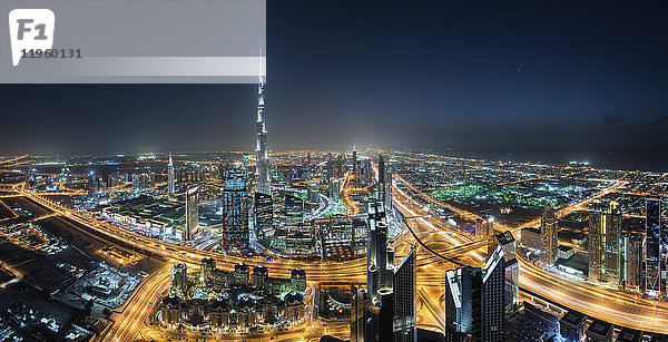 Stadtbild von Dubai  Vereinigte Arabische Emirate bei Nacht  mit dem Wolkenkratzer Burj Khalifa in der Ferne.