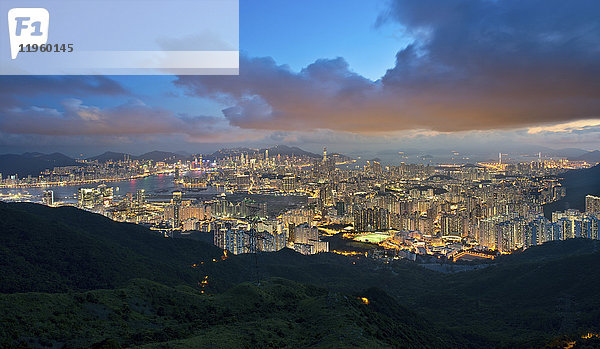 Blick über Kowloon mit der Stadt Hongkong mit beleuchteten Wolkenkratzern in der Abenddämmerung.