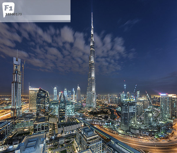 Stadtbild von Dubai  Vereinigte Arabische Emirate in der Abenddämmerung  mit dem Wolkenkratzer Burj Khalifa und beleuchteten Gebäuden im Zentrum.