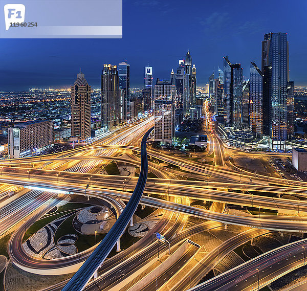 Stadtlandschaft von Dubai  Vereinigte Arabische Emirate in der Dämmerung  mit Wolkenkratzern und beleuchteten Autobahnen im Vordergrund.