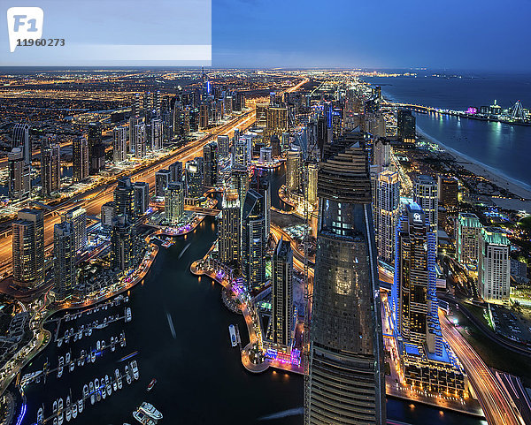 Luftaufnahme des Stadtbildes von Dubai  Vereinigte Arabische Emirate in der Abenddämmerung  mit beleuchteten Wolkenkratzern und dem Yachthafen im Vordergrund.