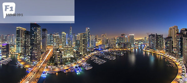Stadtbild von Dubai  Vereinigte Arabische Emirate in der Abenddämmerung  mit beleuchteten Wolkenkratzern und dem Yachthafen im Vordergrund.