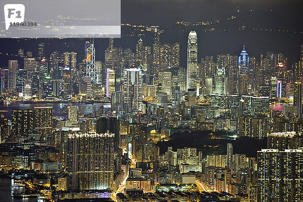 Luftaufnahme des Stadtbildes von Hongkong mit beleuchteten Wolkenkratzern in der Abenddämmerung.