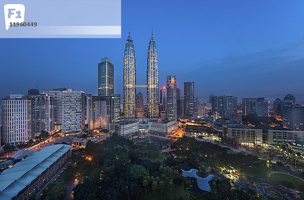 Stadtlandschaft von Kuala Lumpur  Malaysia in der Abenddämmerung  mit beleuchteten Petronas-Türmen in der Ferne.
