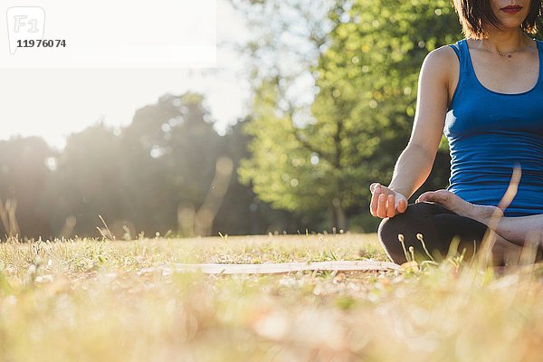 Reife Frau im Park  in Yogastellung sitzend  Blickwinkel tief