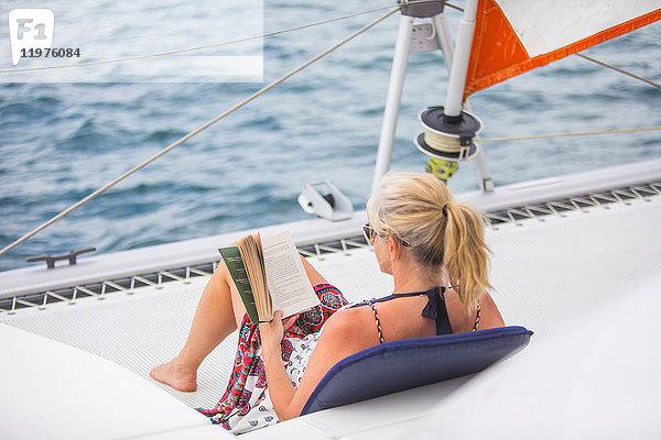 Rückansicht einer Frau  die sich auf einer Yacht entspannt  Lesebuch  Ban Koh Lanta  Krabi  Thailand  Asien