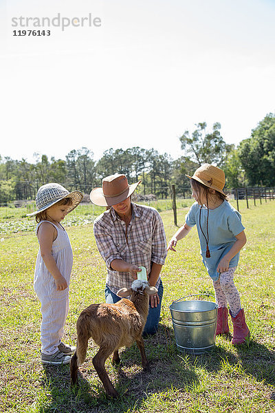 Mutter und zwei Kinder auf dem Bauernhof  Flaschenfütterung junger Ziegen
