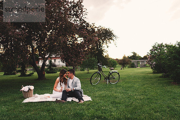 Romantisches junges Paar beim rosa Champagner-Picknick im Park in der Abenddämmerung