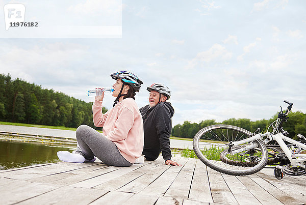 Ein erwachsenes Paar entspannt sich auf dem Steg  Fahrräder neben sich