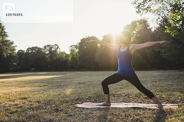 Reife Frau im Park  stehend in Yogastellung  Arme ausgestreckt