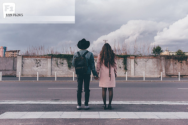 Junges Paar auf der Straße stehend  Hände haltend  Rückansicht