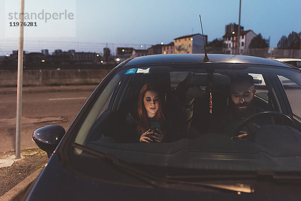 Paar im Auto in der Nacht mit Smartphone