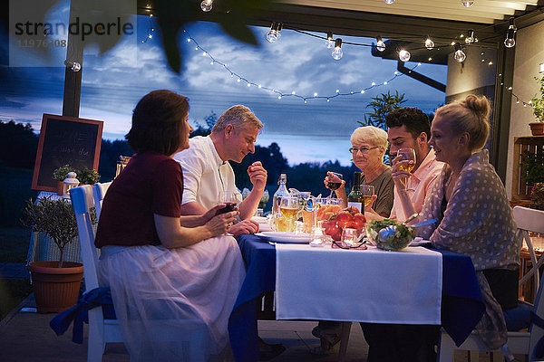 Gruppe von Menschen im Freien  die am Tisch sitzen und das Essen genießen