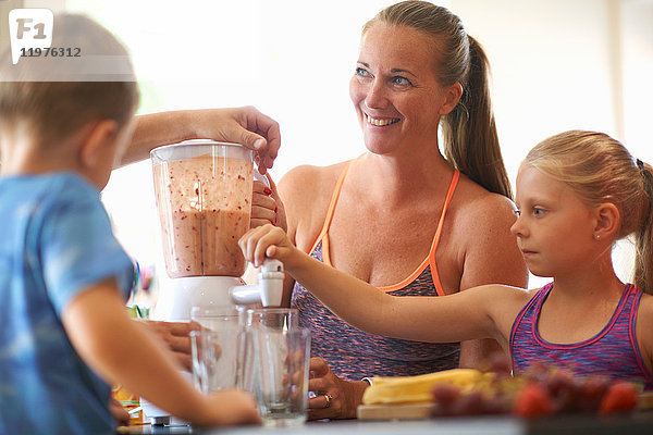 Reife Frau und Kinder mischen frischen Smoothie in der Küche