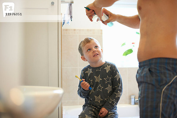 Junge im Badezimmer mit Vater  der sich zum Zähneputzen vorbereitet