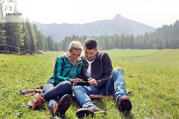 Vor Ort sitzendes Ehepaar mit Blick auf das Smartphone  Tirol  Steiermark  Österreich  Europa