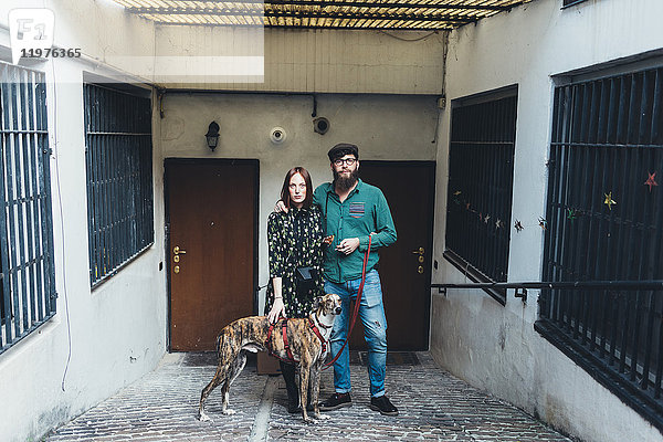 Porträt eines coolen Paares mit Hund vor der Wohnung
