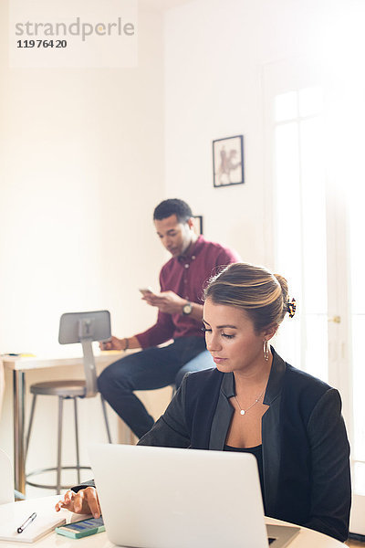 Junge Geschäftsfrau mit Laptop am Büroschreibtisch