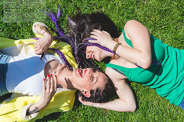 Frauen liegen lachend im Gras