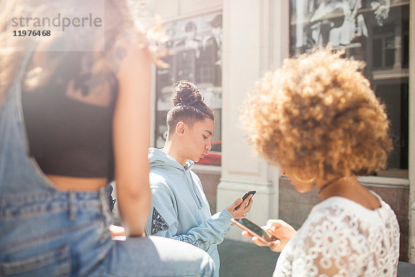 Drei junge Freunde im Freien  die sich Smartphones anschauen