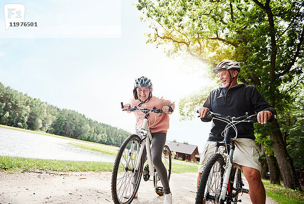 Älteres Ehepaar mit Fahrrad am See  lachend  Blick aus niedrigem Winkel