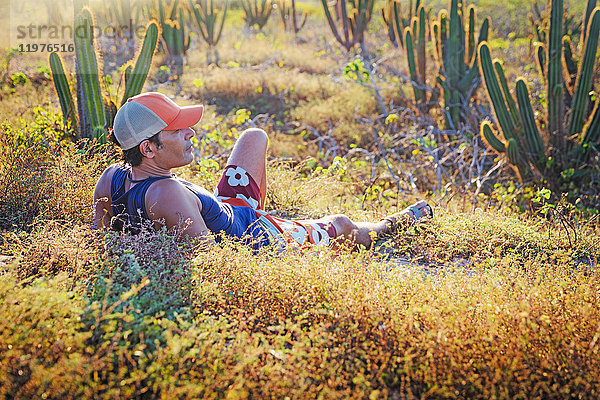 Mann entspannt sich im Gras  umgeben von Kakteen  Jericoacoara-Nationalpark  Ceara  Brasilien
