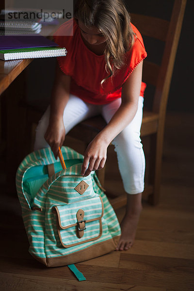 Mädchen packt Rucksack mit Schulsachen