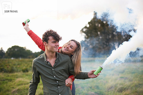 Junges Paar lässt auf dem Feld Rauchfahnen ab