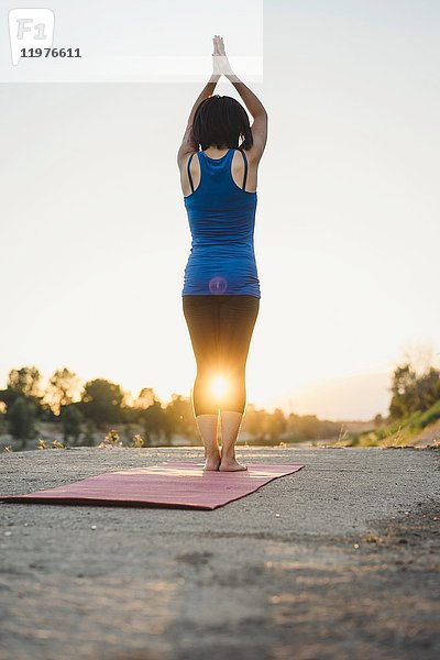 Reife Frau im Freien  stehend in Yogastellung  Rückansicht