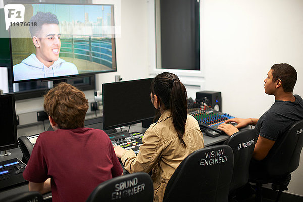 Junge männliche und weibliche College-Studenten am Mischpult beim Fernsehen