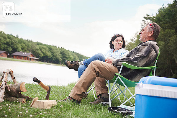 Älteres Paar sitzt in Campingstühlen am See