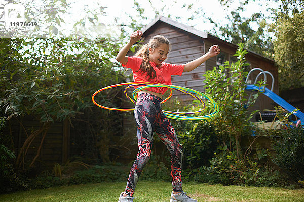 Teenager-Mädchen beim Hula-Hoop-Reifen mit vier Plastikreifen im Garten