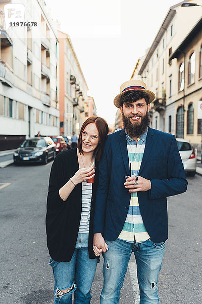Porträt eines glücklichen Paares mit Cocktails auf der Strasse der Stadt
