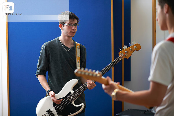 Junge männliche College-Studenten spielen Gitarre im Aufnahmestudio