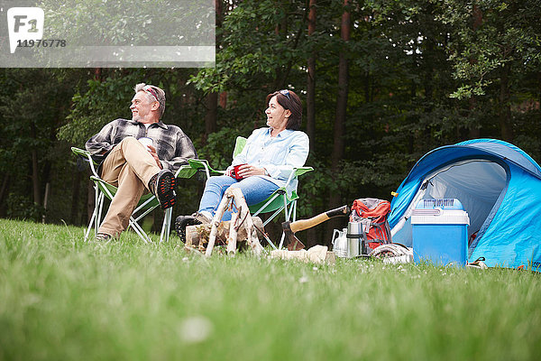 Älteres Paar sitzt in Campingsesseln neben dem Zelt  Blickwinkel niedrig